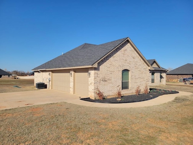 view of property exterior featuring roof with shingles, concrete driveway, a garage, central air condition unit, and brick siding