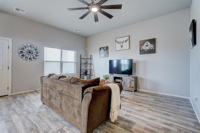 living room with visible vents, baseboards, light wood-style flooring, and a ceiling fan