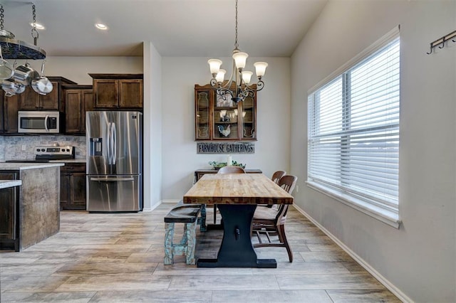 dining space with a notable chandelier, recessed lighting, light wood-type flooring, and baseboards
