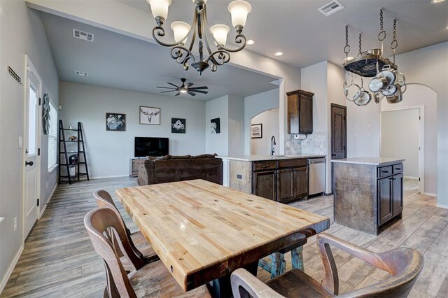 dining area featuring ceiling fan with notable chandelier, light wood-style flooring, arched walkways, and visible vents