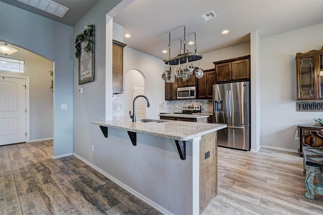 kitchen with visible vents, arched walkways, a sink, stainless steel appliances, and a kitchen breakfast bar