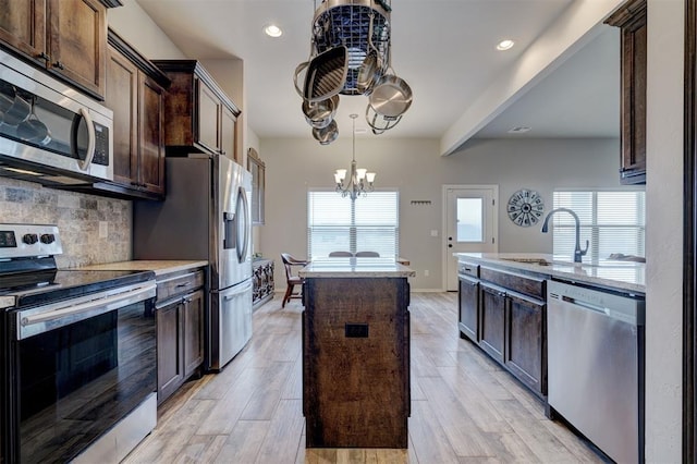 kitchen with tasteful backsplash, a kitchen island, dark brown cabinetry, a chandelier, and appliances with stainless steel finishes