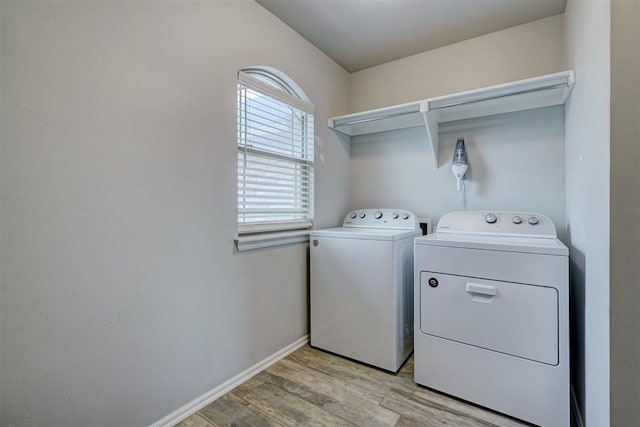 washroom with laundry area, washing machine and dryer, baseboards, and light wood-style floors