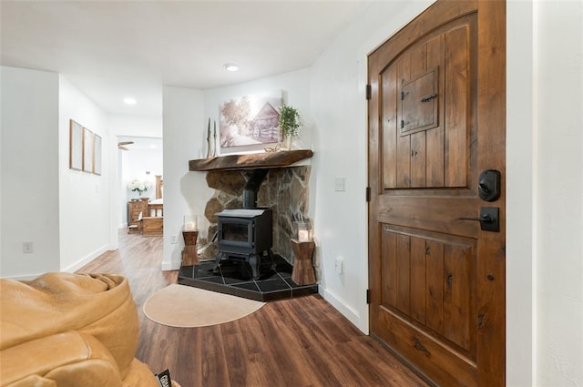 living room with recessed lighting, baseboards, dark wood-style flooring, and a wood stove