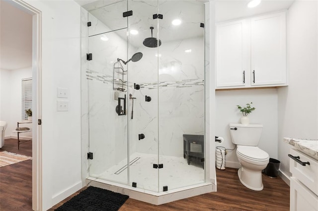 full bath featuring a marble finish shower, baseboards, toilet, and wood finished floors