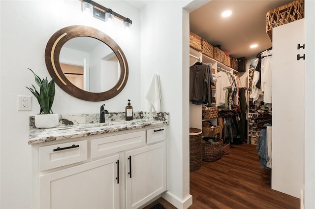 bathroom with a walk in closet, vanity, recessed lighting, and wood finished floors