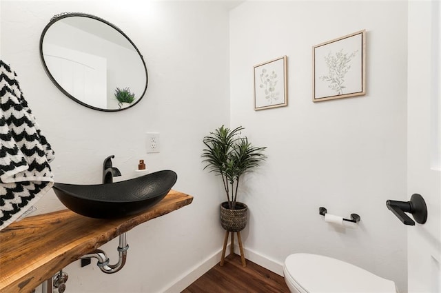 bathroom with a sink, baseboards, toilet, and wood finished floors