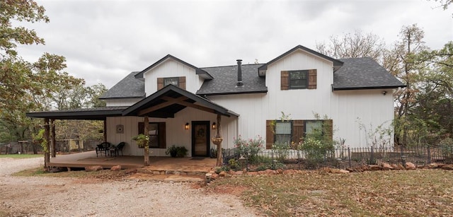 modern inspired farmhouse with a shingled roof and fence