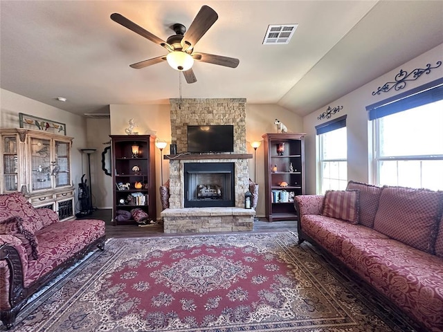 living room featuring visible vents, wood finished floors, a fireplace, lofted ceiling, and ceiling fan