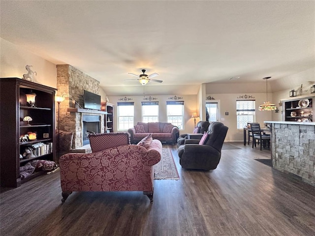 living room with dark wood finished floors, a fireplace, a wealth of natural light, and a ceiling fan