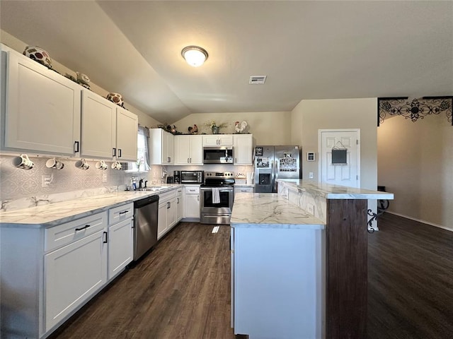 kitchen featuring lofted ceiling, a sink, decorative backsplash, appliances with stainless steel finishes, and a center island