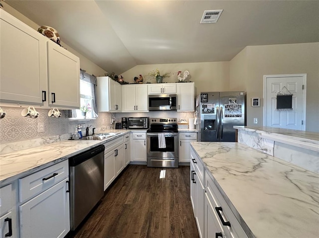 kitchen featuring visible vents, light stone countertops, decorative backsplash, stainless steel appliances, and a sink