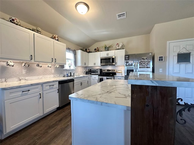 kitchen featuring visible vents, a kitchen island, lofted ceiling, appliances with stainless steel finishes, and backsplash