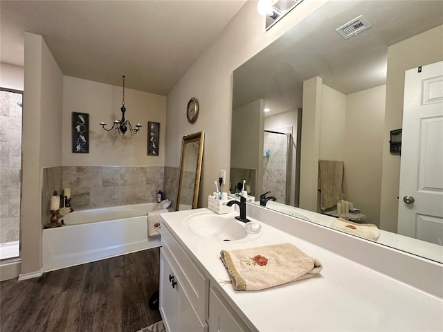 full bathroom featuring visible vents, a shower stall, wood finished floors, a bath, and vanity