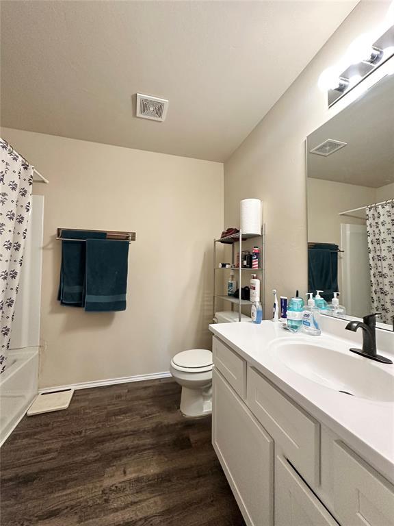 full bathroom with visible vents, toilet, vanity, and wood finished floors