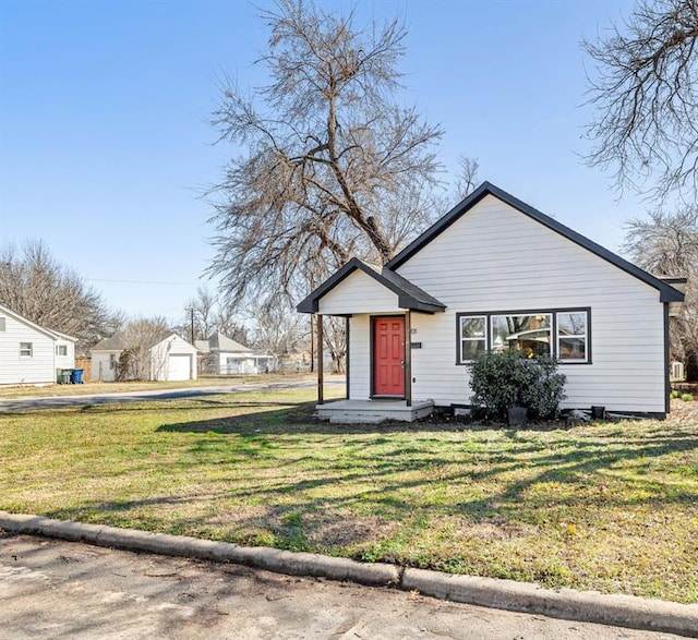 bungalow-style home featuring a front yard and an outdoor structure