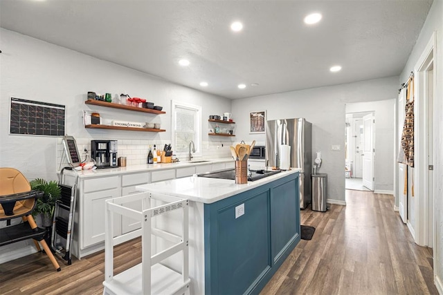 kitchen featuring wood finished floors, black cooktop, open shelves, a sink, and a center island