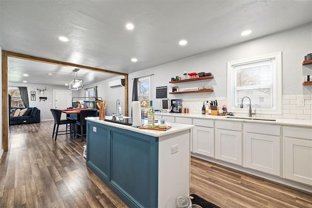 kitchen featuring a sink, plenty of natural light, a wall mounted air conditioner, and open shelves