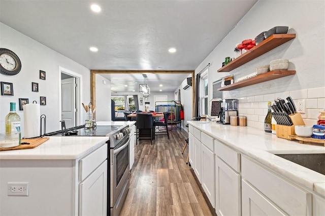 kitchen featuring a wall mounted AC, open shelves, stainless steel electric stove, wood finished floors, and white cabinets