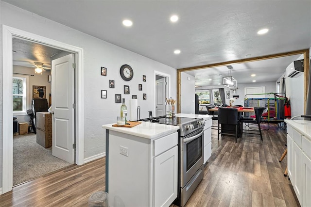 kitchen featuring a kitchen island, recessed lighting, stainless steel range with electric stovetop, wood finished floors, and white cabinets