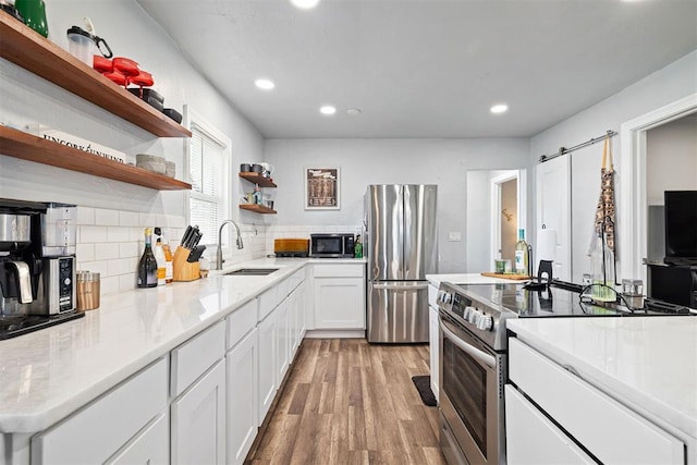 kitchen featuring open shelves, a sink, white cabinetry, light wood-style floors, and appliances with stainless steel finishes