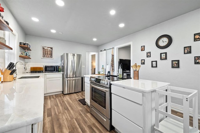 kitchen with open shelves, light wood-style flooring, a sink, white cabinets, and appliances with stainless steel finishes