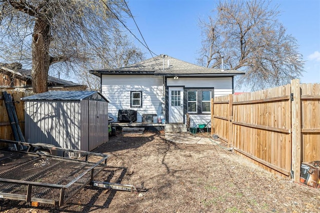 rear view of property with a storage unit, entry steps, fence, roof with shingles, and an outdoor structure