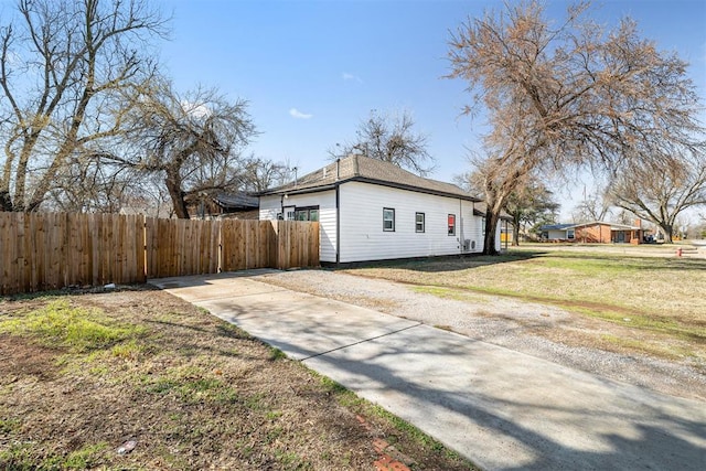 view of side of home featuring fence and a lawn