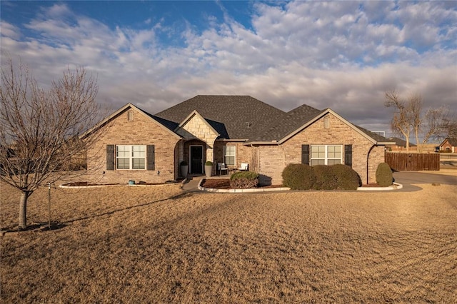 view of front of house with brick siding and roof with shingles