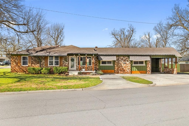 view of front facade with brick siding, concrete driveway, a front yard, and a carport