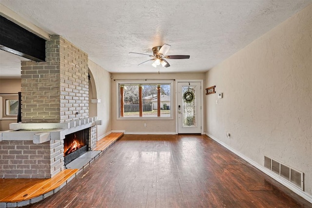 unfurnished living room featuring visible vents, a fireplace, ceiling fan, and a textured wall