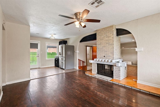 unfurnished living room featuring visible vents, a ceiling fan, a textured ceiling, arched walkways, and wood-type flooring