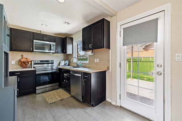 kitchen with visible vents, a sink, decorative backsplash, light countertops, and appliances with stainless steel finishes