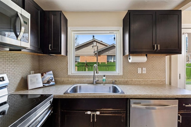 kitchen featuring tasteful backsplash, stainless steel appliances, light countertops, and a sink