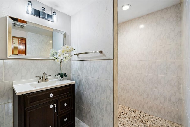 full bathroom with vanity, tile walls, a walk in shower, and visible vents