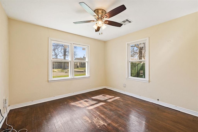 spare room featuring hardwood / wood-style floors, baseboards, visible vents, and a ceiling fan