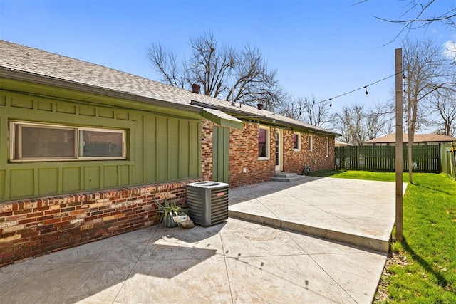 exterior space featuring fence, a yard, central air condition unit, a patio area, and board and batten siding