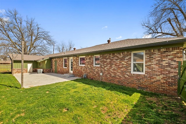 rear view of property with a patio, fence, a yard, central air condition unit, and brick siding