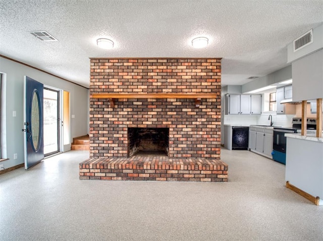 unfurnished living room with a brick fireplace, baseboards, visible vents, and a textured ceiling