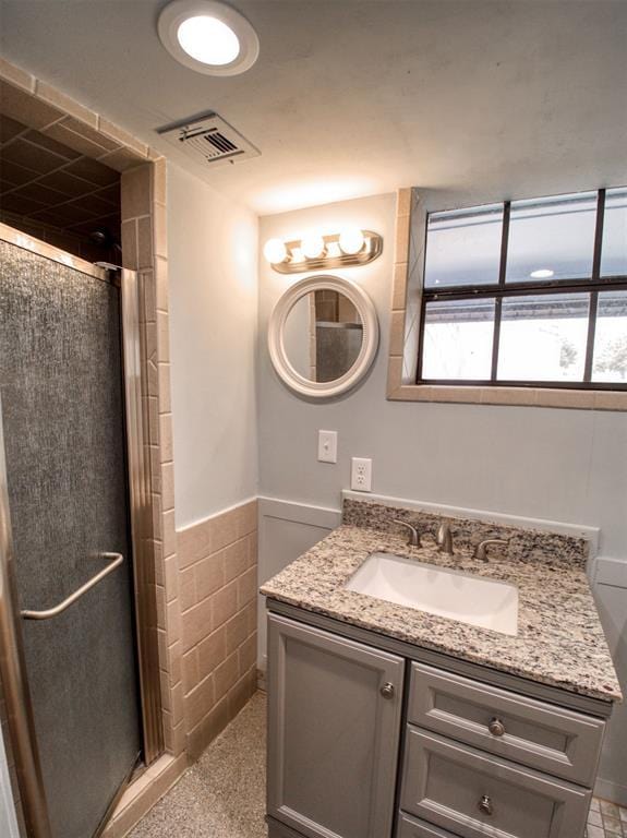 bathroom with visible vents, a shower stall, vanity, and a wainscoted wall