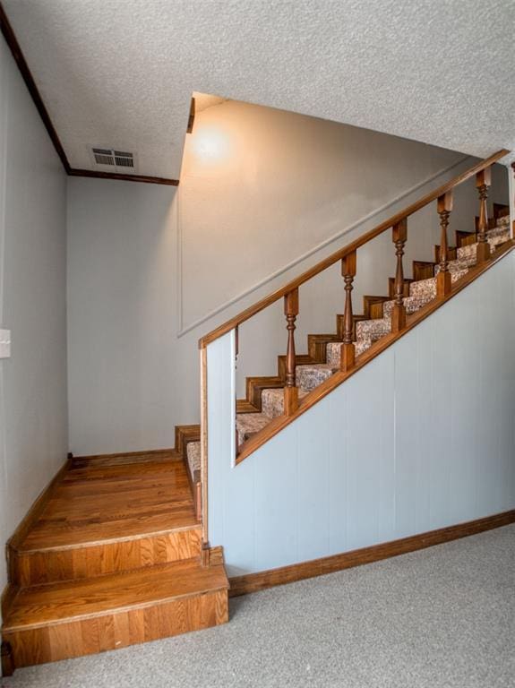 stairs featuring visible vents, a textured ceiling, and carpet