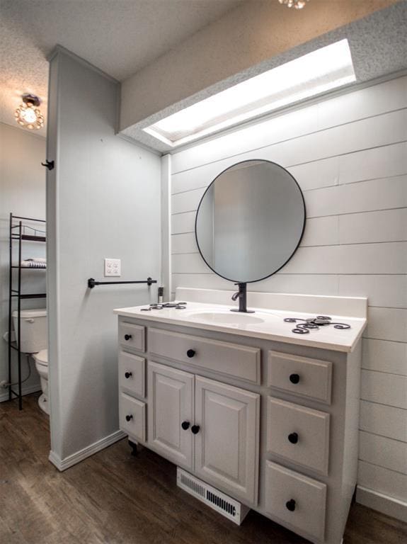 bathroom featuring visible vents, toilet, wood finished floors, baseboards, and vanity