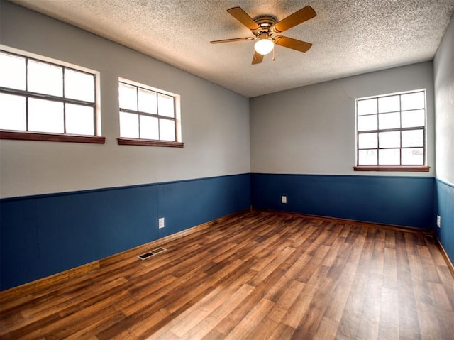 unfurnished room featuring ceiling fan, wood finished floors, visible vents, and a textured ceiling