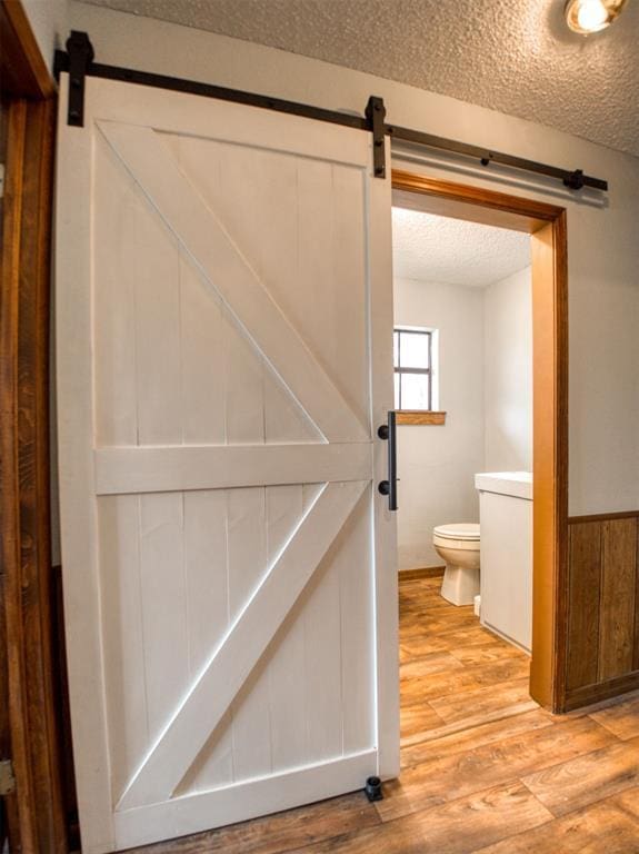 interior space featuring a textured ceiling, wood finished floors, and toilet