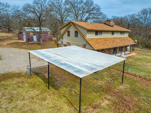 exterior space featuring an outbuilding, fence, a yard, gravel driveway, and a chimney