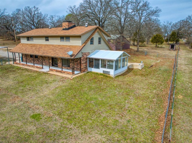 rear view of house featuring fence, roof with shingles, a yard, a sunroom, and a chimney