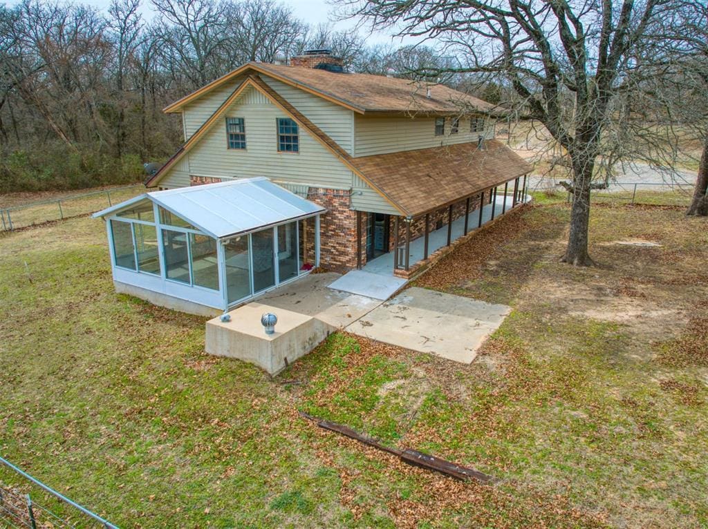1600 S Indian Rd, Wewoka, OK 74884 - rear view of house featuring a chimney, fence, a shingled roof, a sunroom, and a yard