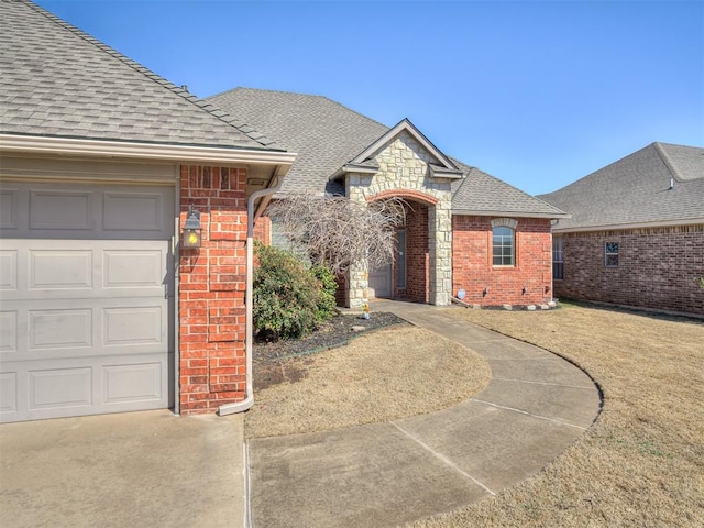 french country inspired facade with an attached garage, brick siding, stone siding, and a shingled roof