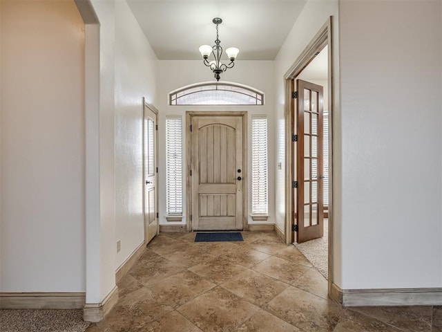 foyer with baseboards, arched walkways, and an inviting chandelier