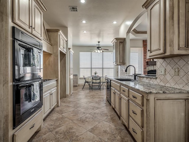 kitchen featuring visible vents, dobule oven black, a sink, backsplash, and wine cooler